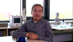Büro mit Büchern, Statue, Monitor auf Fensterbank, Kaffeetasse auf Tisch.
