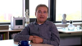 Prof. Onur Güntürkün (Fellow of the Max Planck Schools of Cognition), speaking about his "Passion for Science" at the Max Planck Schools Day 2020. Büro mit Büchern, Statue, Monitor auf Fensterbank, Kaffeetasse auf Tisch.