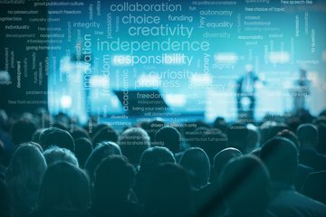 The image shows an audience in front of a stage, with floating keywords in the background such as “collaboration,” “creativity,” and “independence.”