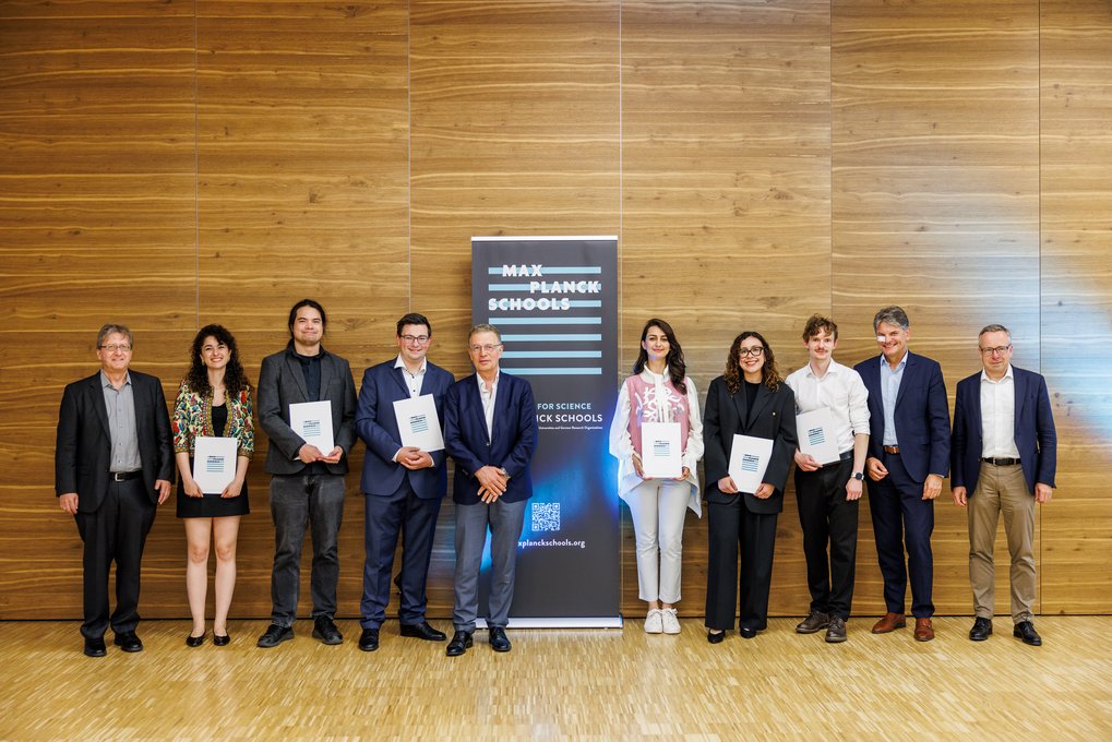 Gruppe vor einem Max Planck Schools Banner, mehrere halten Zertifikate.