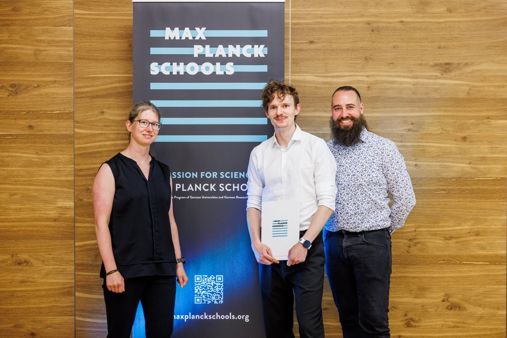 Holzpaneelwand mit Banner der Max Planck Schools, QR-Code und Text über Wissenschaft.