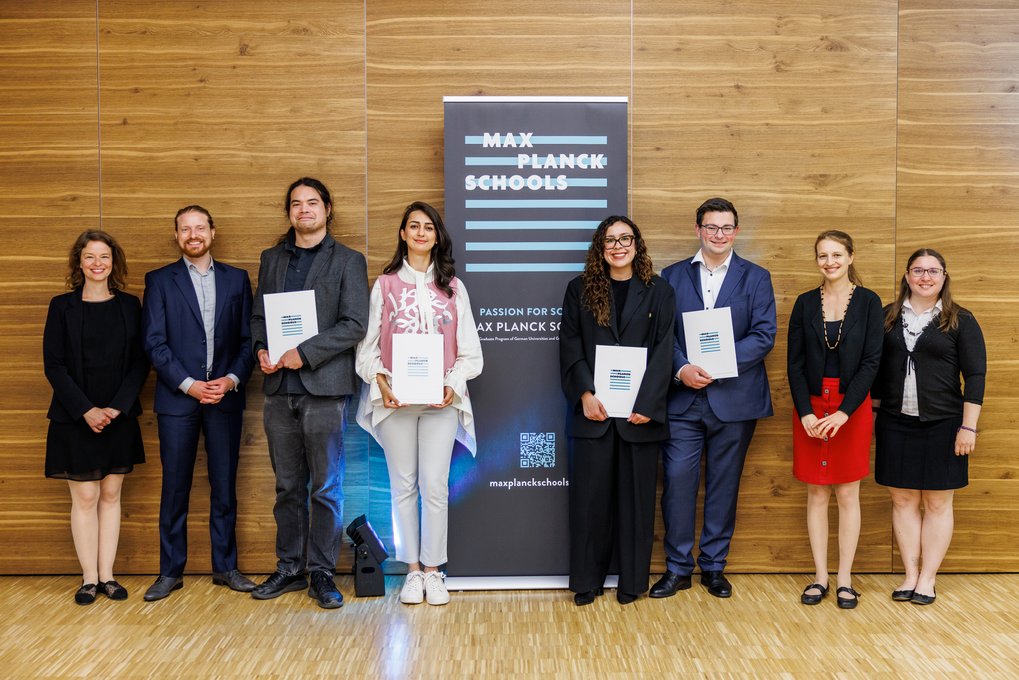 Personen stehen vor einem Banner der Max Planck Schools.