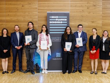 People standing in front of a banner advertising the Max Planck Schools.