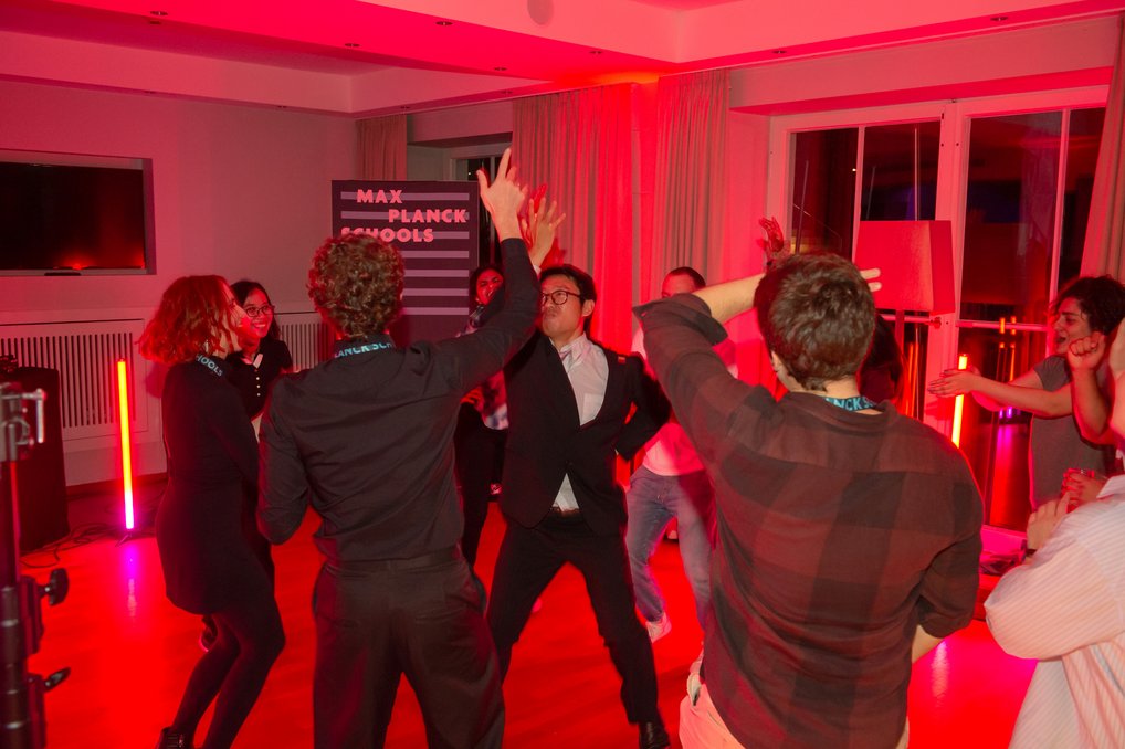 Personen tanzen in einem Raum mit roter Beleuchtung.