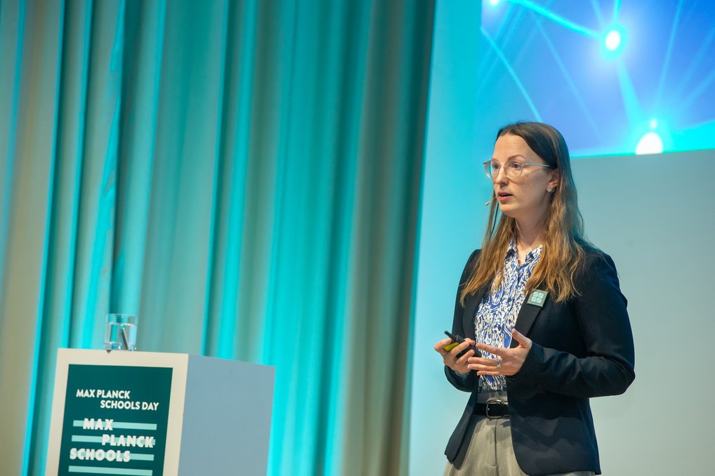 Person hält eine Präsentation neben einem Max Planck Schools Podium.