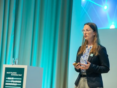 Person hält eine Präsentation neben einem Max Planck Schools Podium.